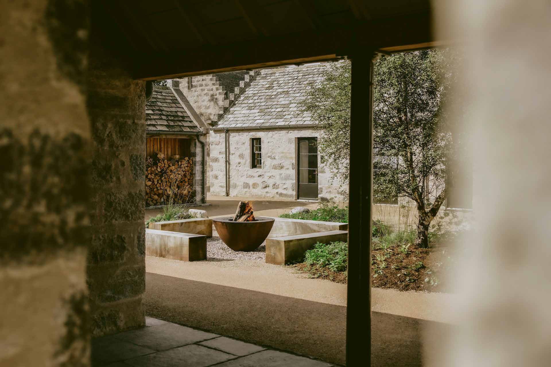 A stone courtyard with a fire bowl, seen from under an archway