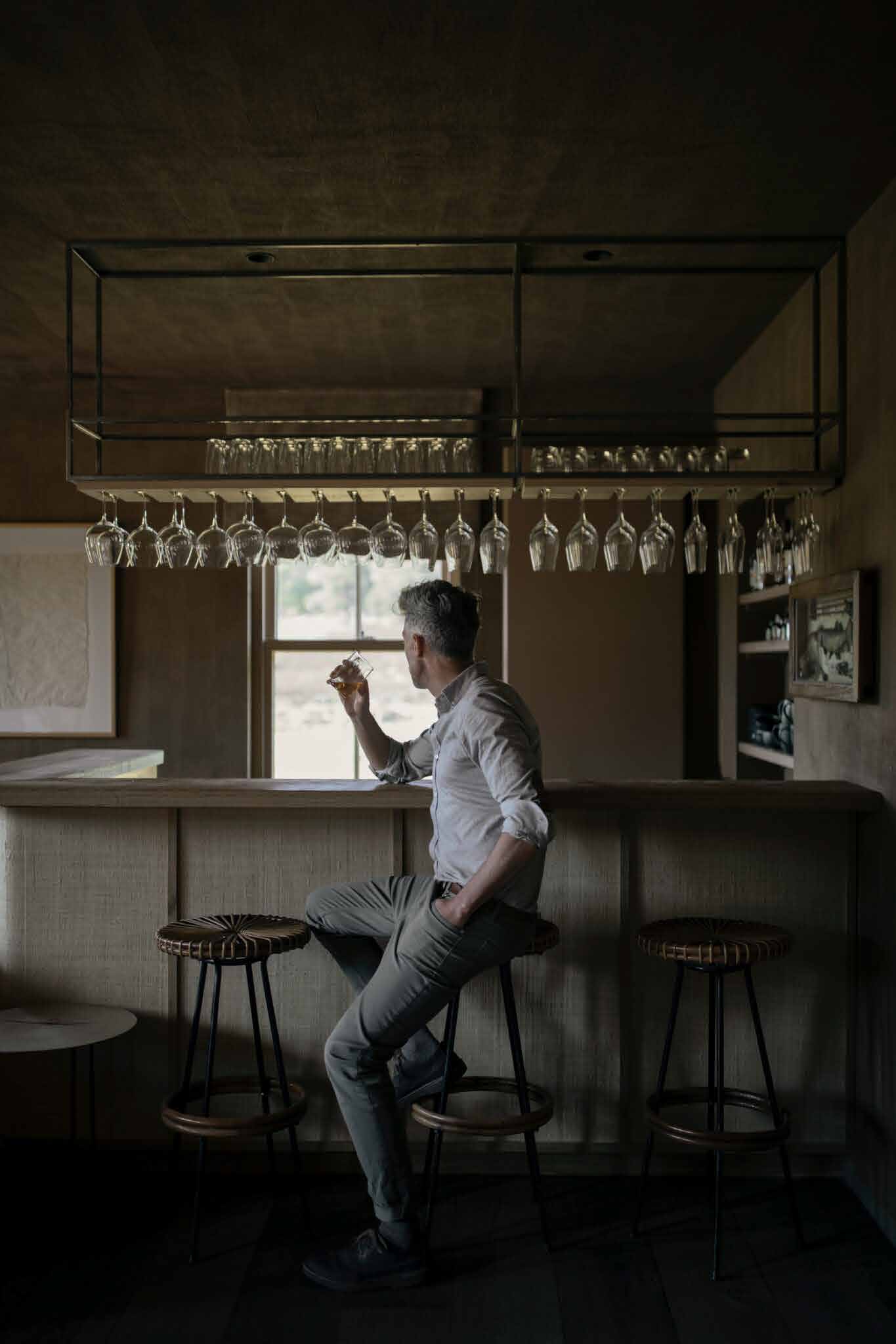 A man with a dram at the bar of a quiet, wood-panelled pub
